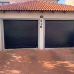 Exterior view of two black aluminium single garage doors on residential home