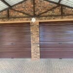 Two brown roll-up garage doors installed on exterior brick building