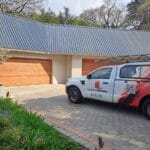 Horizontal slatted meranti double garage doors exterior with Adams Doors service vehicle