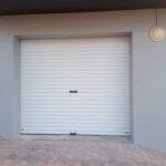 White roll-up garage door installed on exterior wall with clean modern finish
