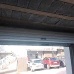 Interior view of white roll-up garage door partially open showing mechanism