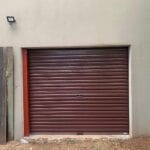 Brown roll-up garage door installed on exterior wall of residential property