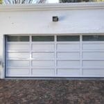 White cladded garage door with top window panels