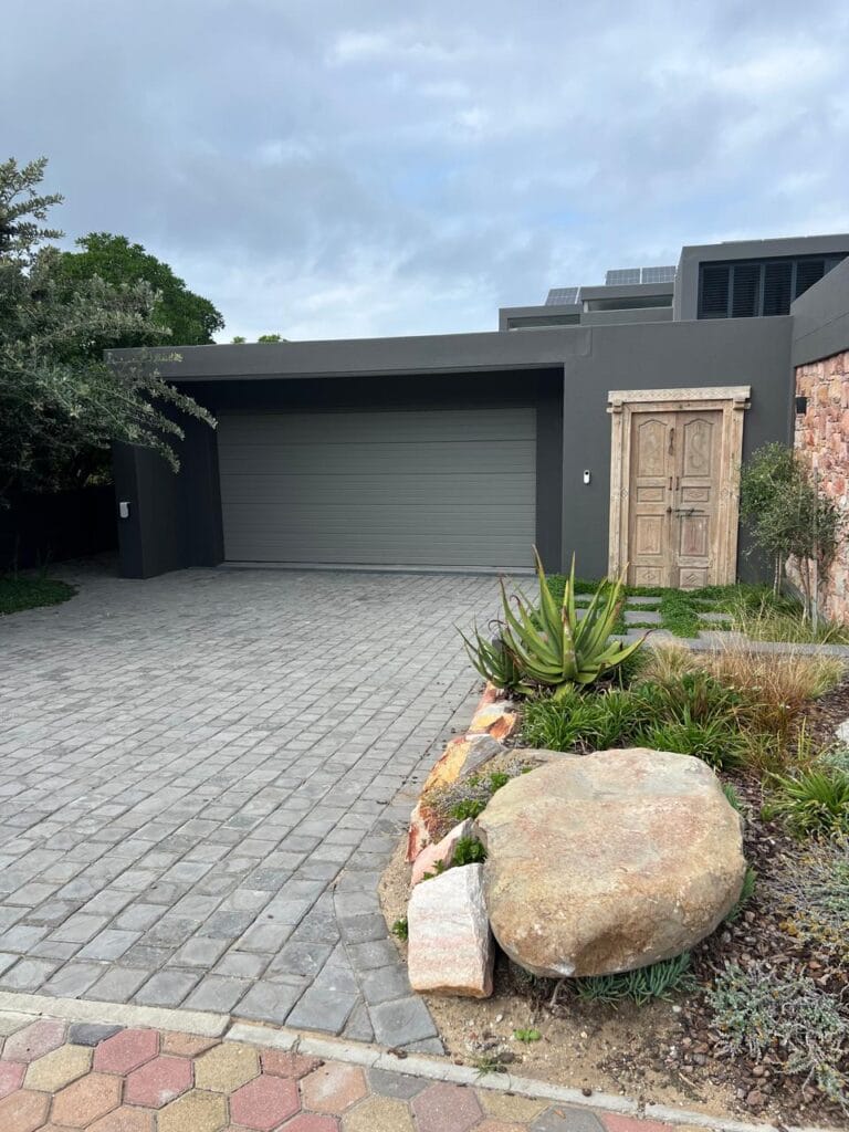 Modern grey aluminium garage door with landscaped driveway and entrance