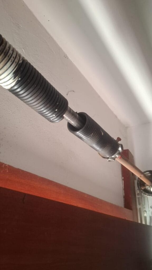 Broken garage door torsion spring on shaft above door