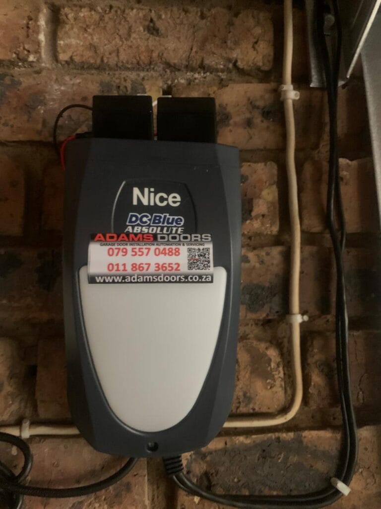 Nice DC Blue Absolute garage door motor installed on wall with battery backup system